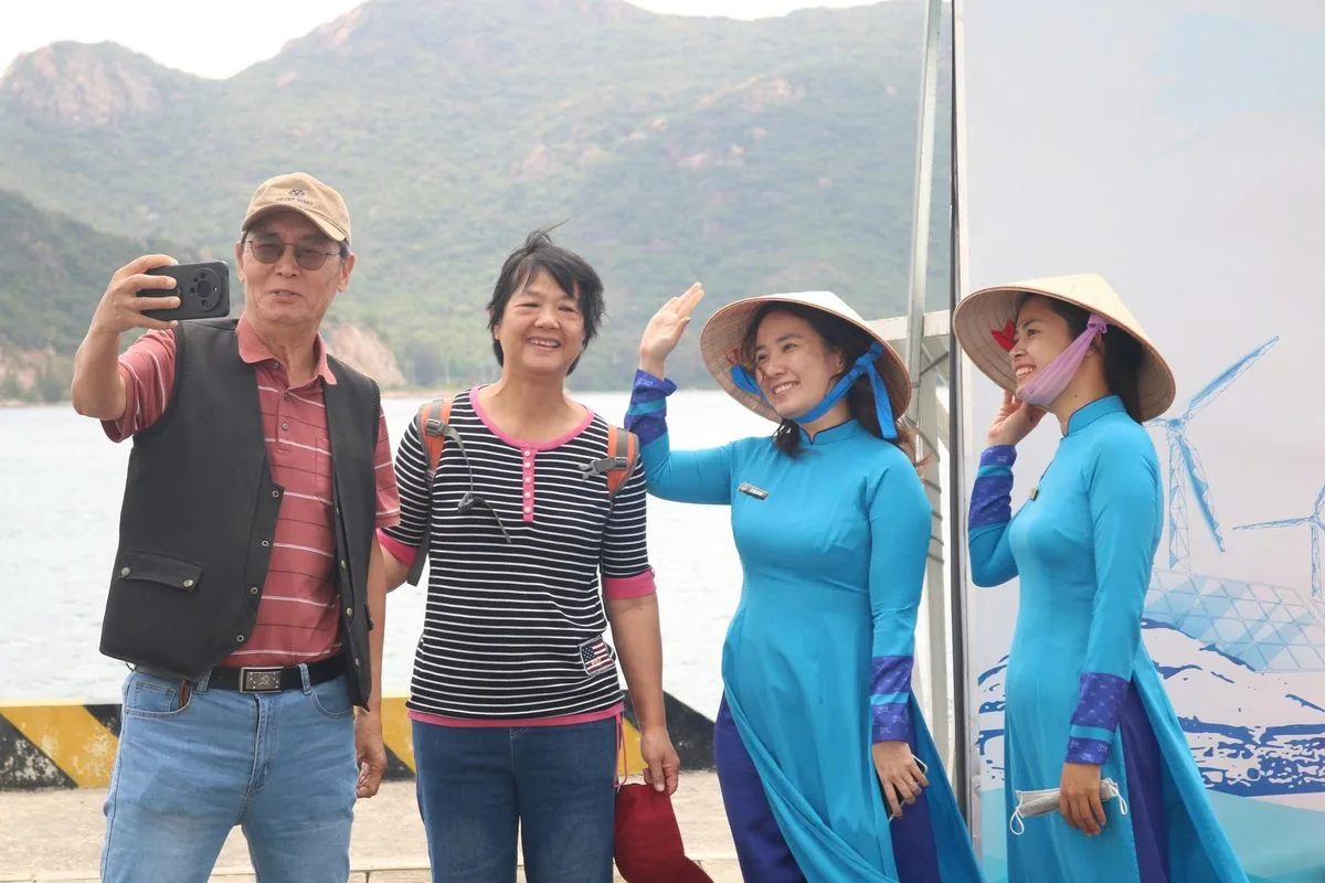 Du kh&aacute;ch quốc tế chụp ảnh selfie với nh&acirc;n vi&ecirc;n đ&oacute;n tiếp mặc &aacute;o d&agrave;i truyền thống tại cảng Cam Ranh
