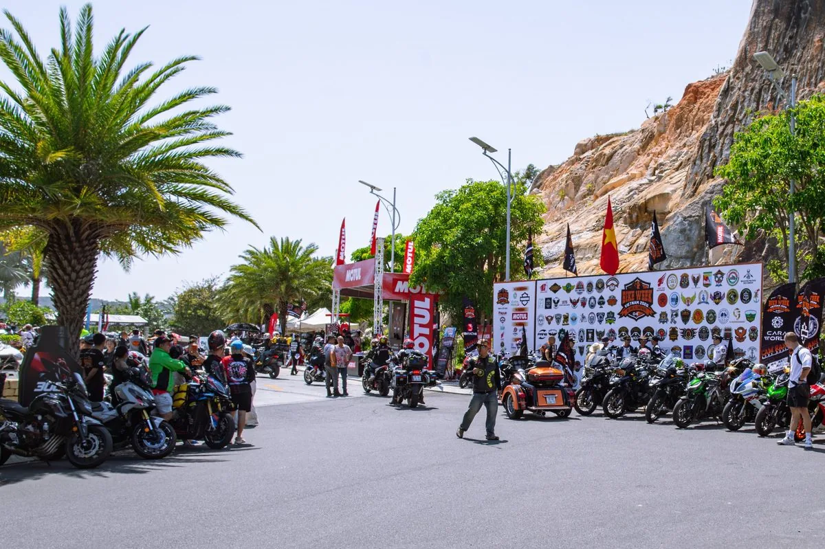 Biker tập trung tại khu vực sự kiện dưới ch&acirc;n n&uacute;i đ&aacute; với backdrop logo c&aacute;c c&acirc;u lạc bộ m&ocirc; t&ocirc; Bike Week 2026