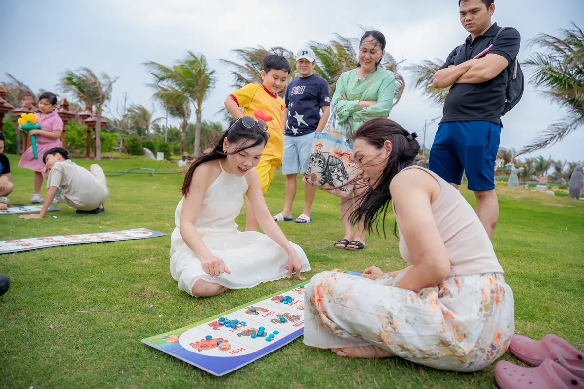Mẹ v&agrave; con g&aacute;i chơi tr&ograve; chơi board game tr&ecirc;n thảm cỏ xanh c&ocirc;ng vi&ecirc;n CaraWorld Cam Ranh