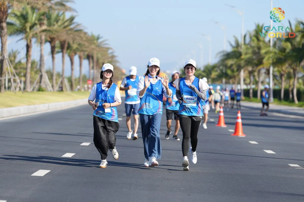 Ba nữ vận động vi&ecirc;n vẫy tay ch&agrave;o đi bộ tr&ecirc;n đại lộ ven biển CaraWorld giải Cara Run 2026