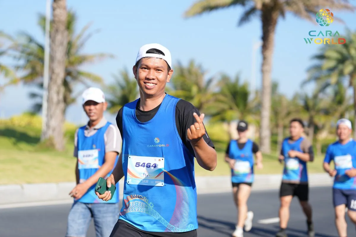 Vận động vi&ecirc;n nam số 5464 mỉm cười giơ tay ch&agrave;o tr&ecirc;n đại lộ cọ dừa CaraWorld Cara Run 2026
